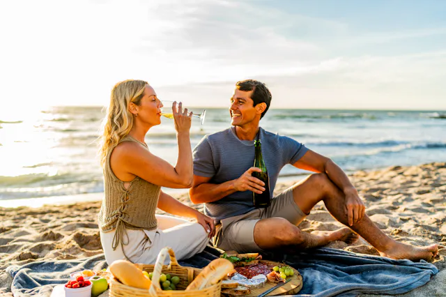 Couple talking and drinking wine during picnic on the beach