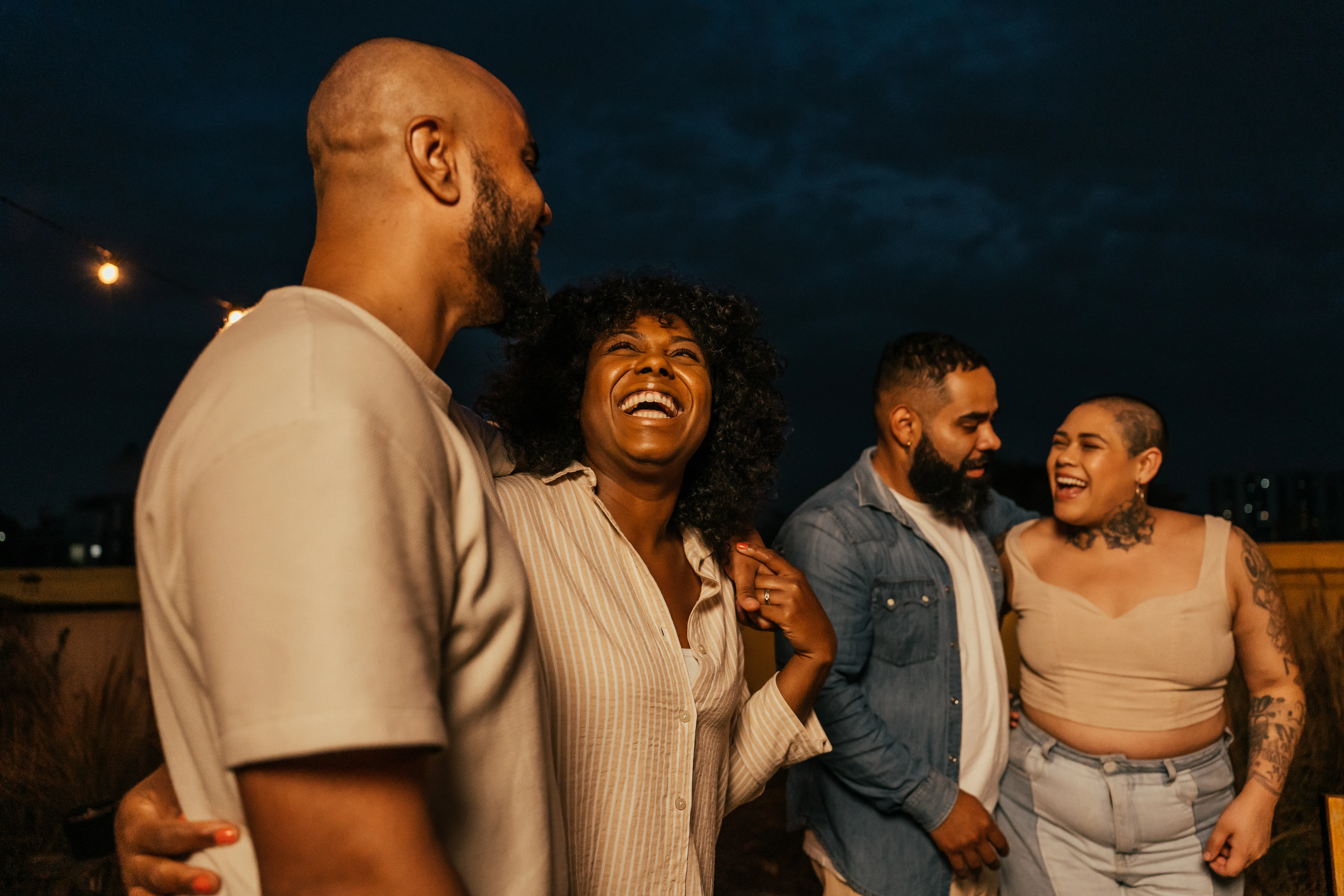 Friends enjoying happy hour, listening to friend playing guitar