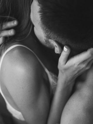 Intimate couple in bed. Kissing with passion and desire. Young lovers on honeymoon. View from behind...