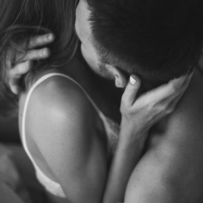 Intimate couple in bed. Kissing with passion and desire. Young lovers on honeymoon. View from behind close up. Unrecognizable person and sexy mood.