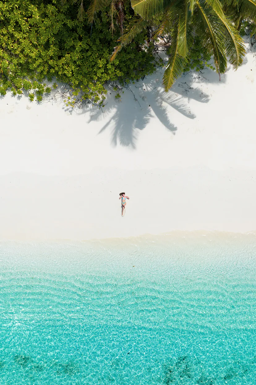Aerial drone view of a woman lying down on a sandy beach