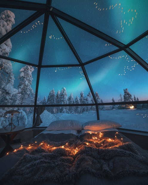Standing on the comfortable bed and watching breathtaking northern lights or Aurora Borealis over a ...