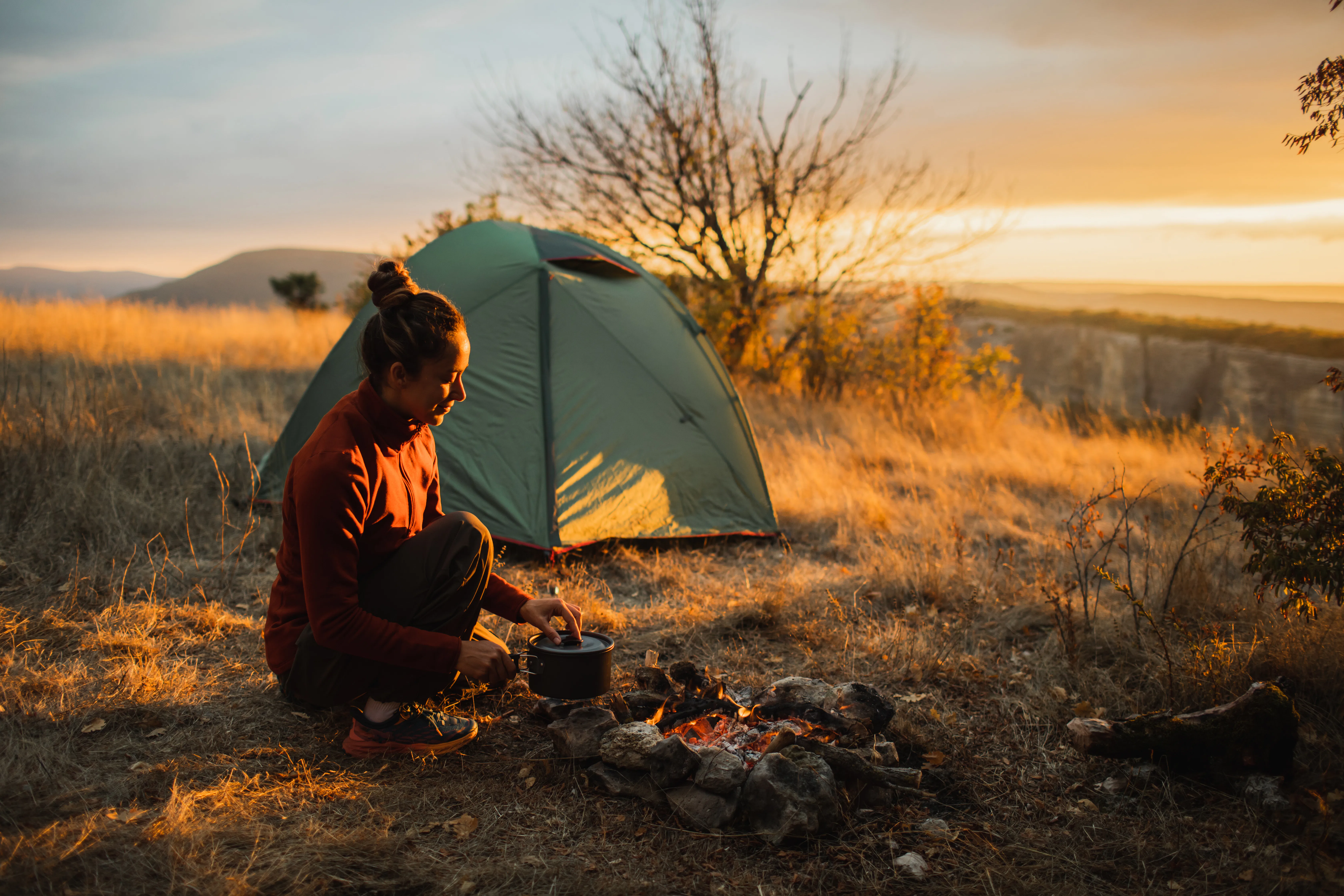 A lone camper sits beside a glowing campfire