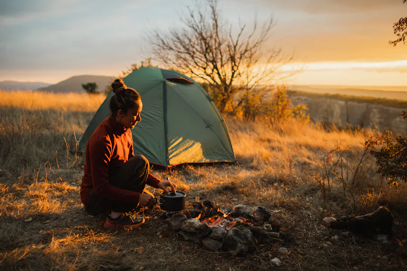 A lone camper sits beside a glowing campfire