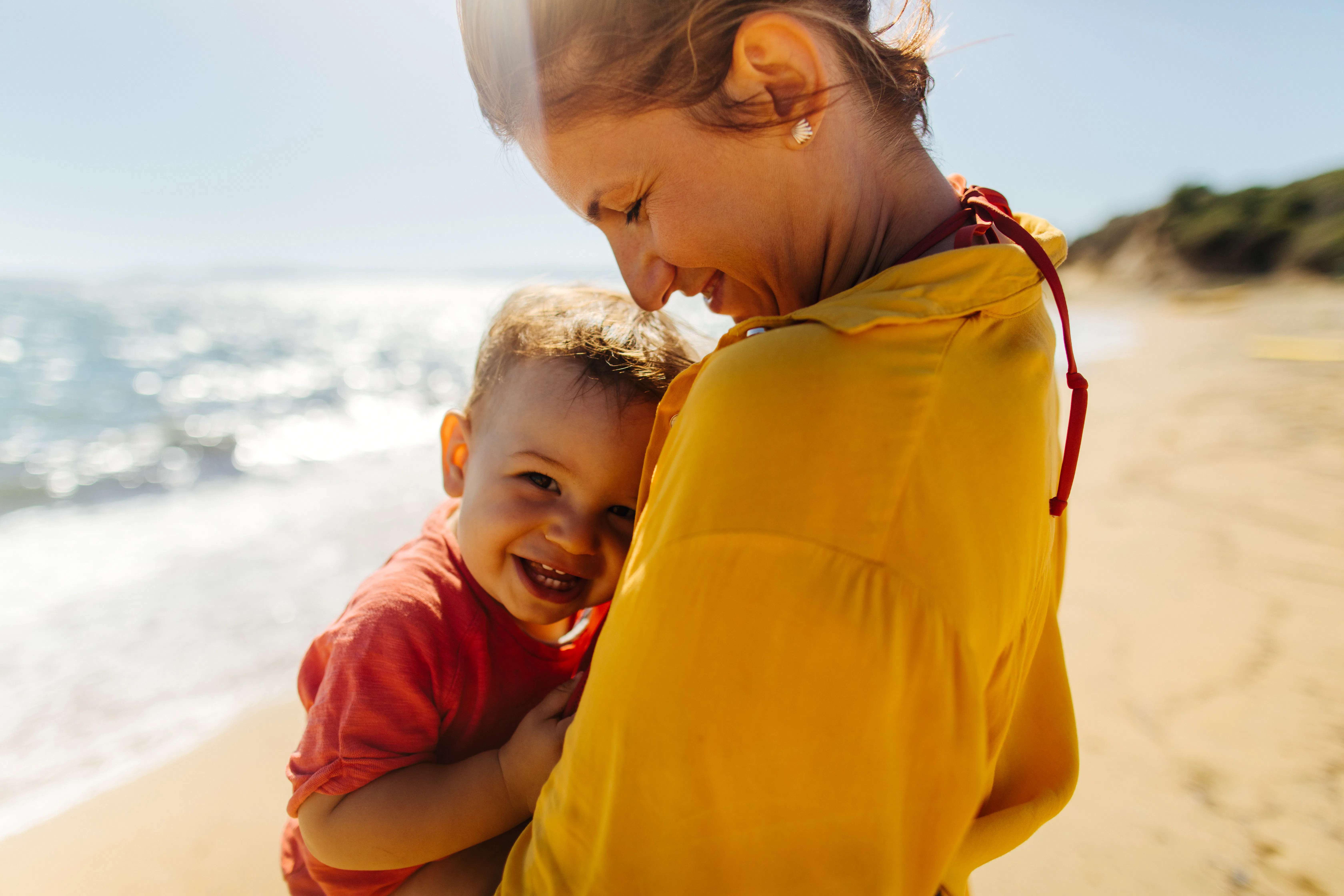 Photo of mother hugging her baby boy while enjoying together at the beach