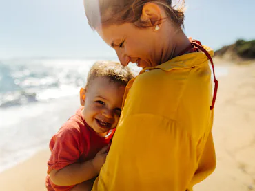 Photo of mother hugging her baby boy while enjoying together at the beach