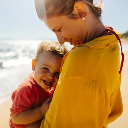 Photo of mother hugging her baby boy while enjoying together at the beach