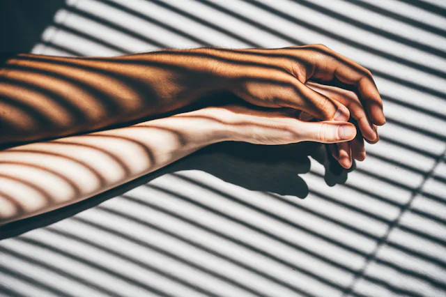 Interracial couple holding hands on the bed.