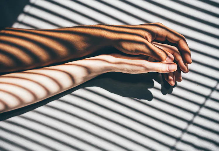 Interracial couple holding hands on the bed.