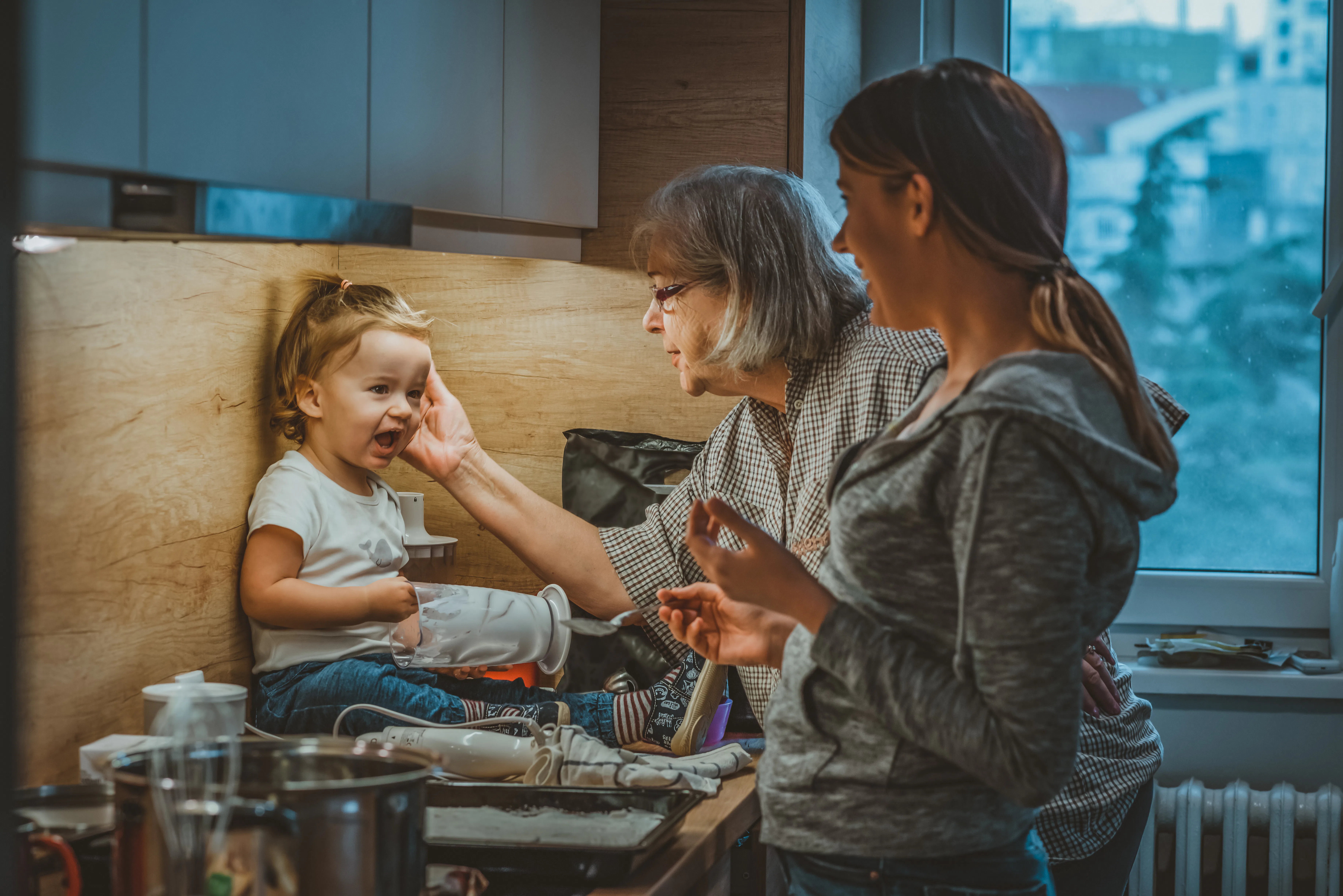 Photo of Grandmother and woman housewife, they feed the baby boy in the kitchen during the day. Youn...