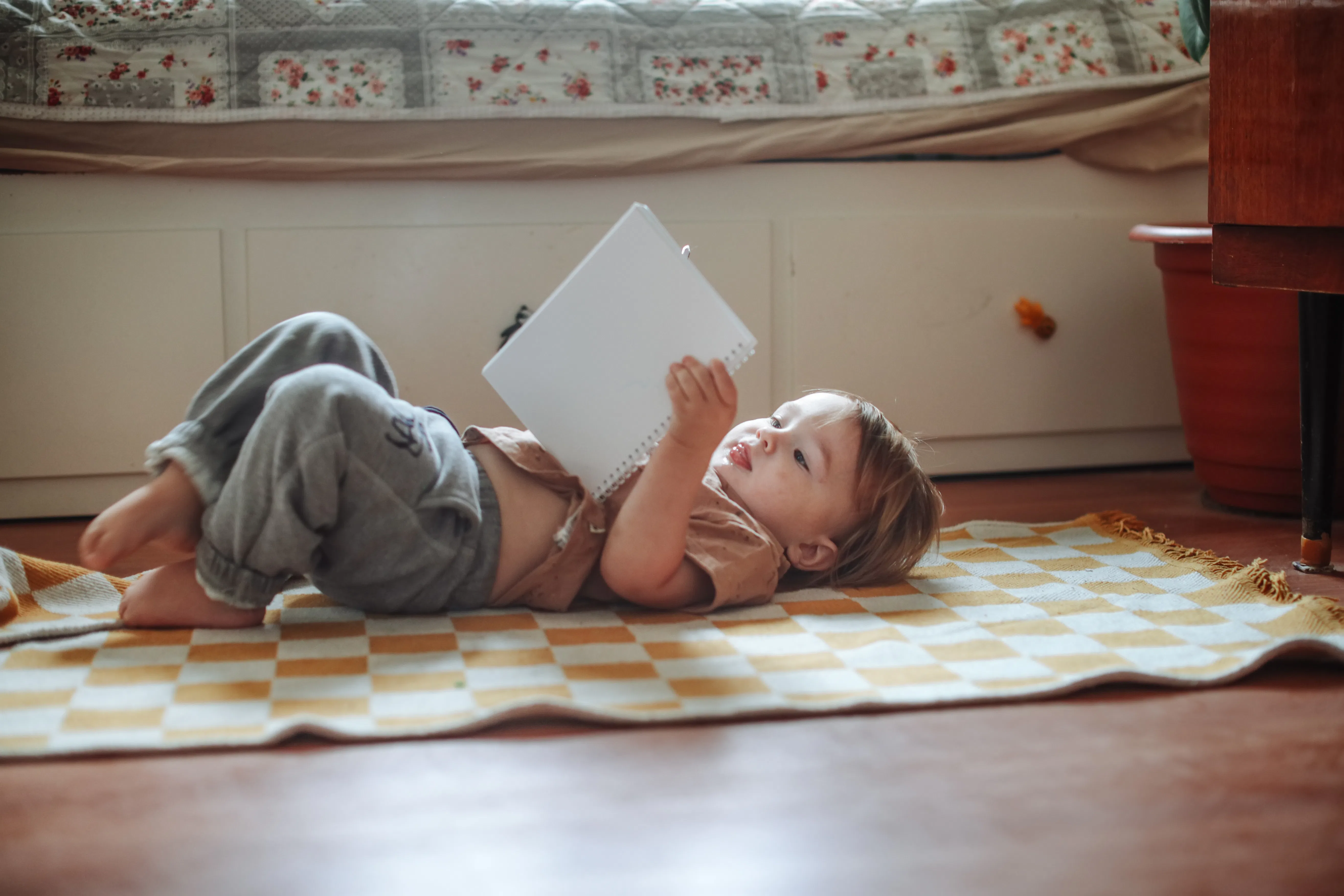 Toddler Lying on the Floor and Reading a Book at Home