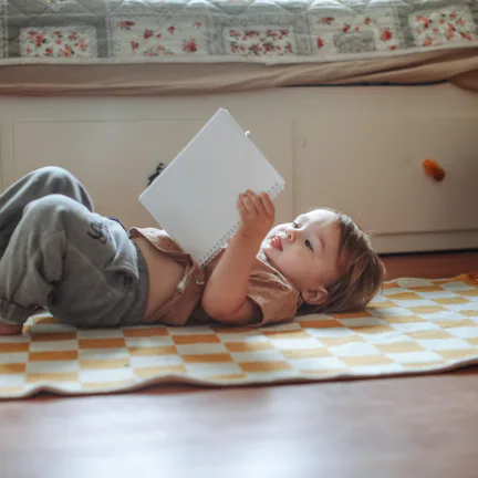 Toddler Lying on the Floor and Reading a Book at Home