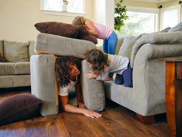 Two little girls, playing in the living room of a home on a play date.