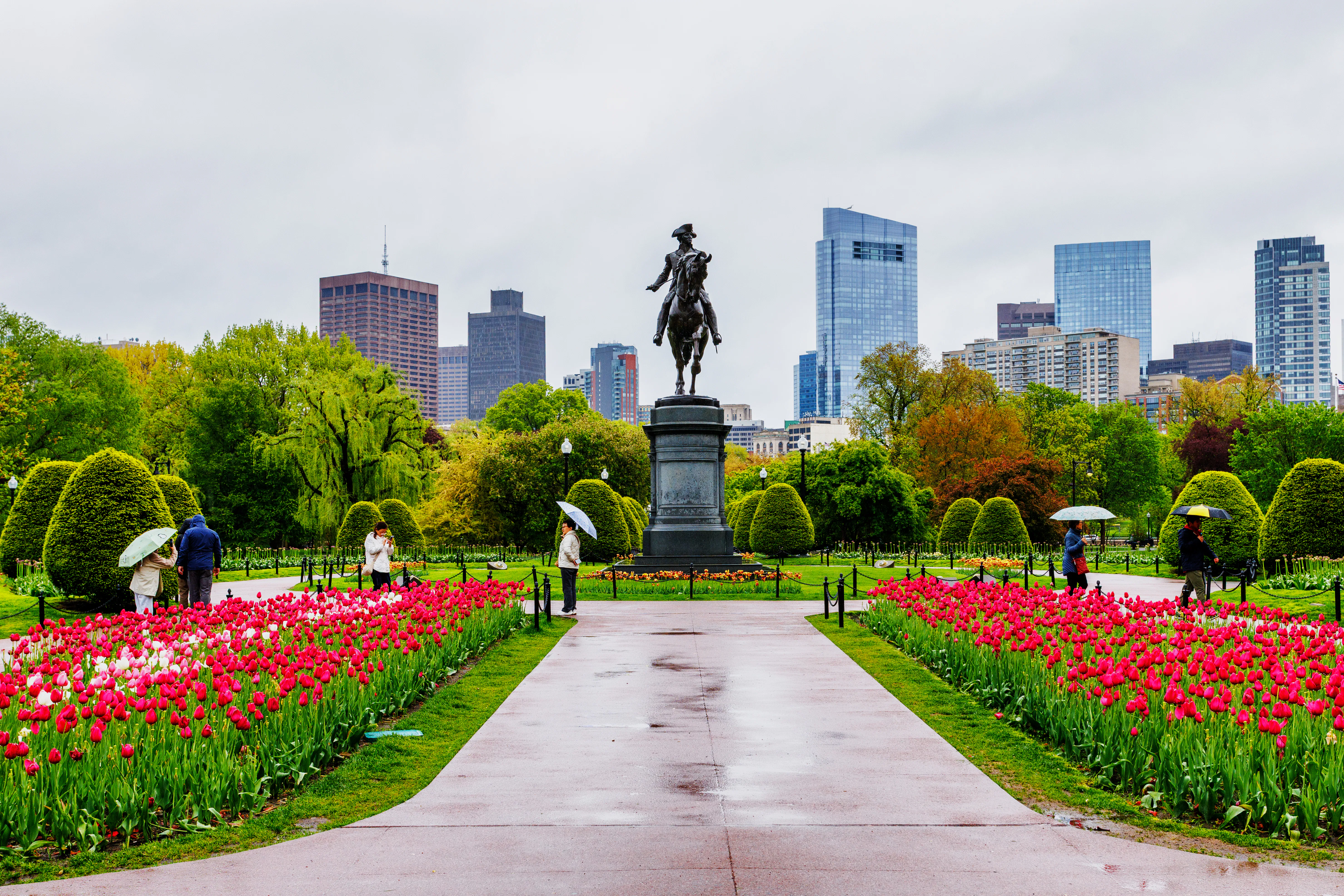 Boston, Massachusetts, USA - May 10, 2025: Tourists with umbrellas on a rainy day in the Boston Publ...