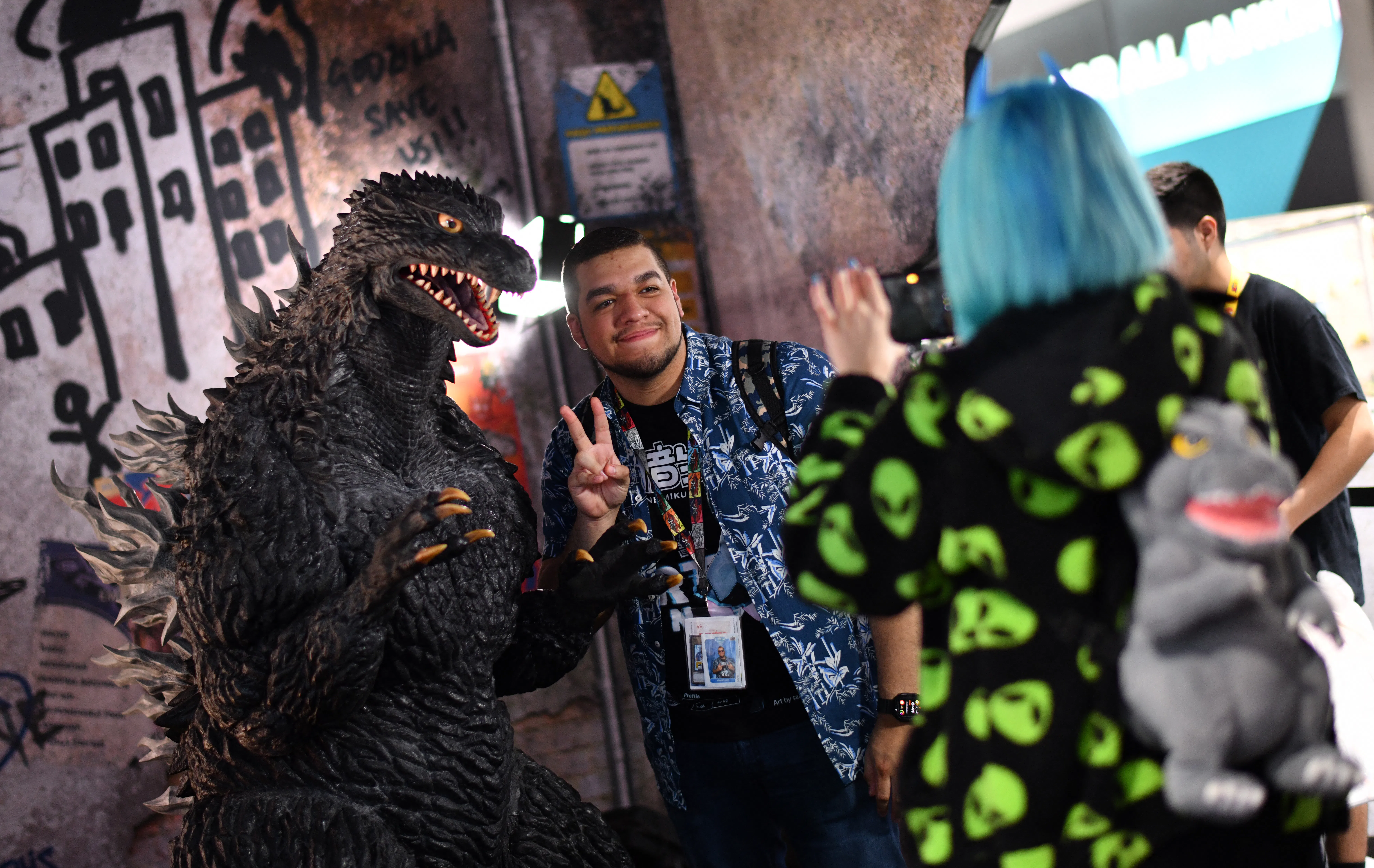 An attendee poses for photos with Godzilla during Comic-Con International in San Diego, California, ...