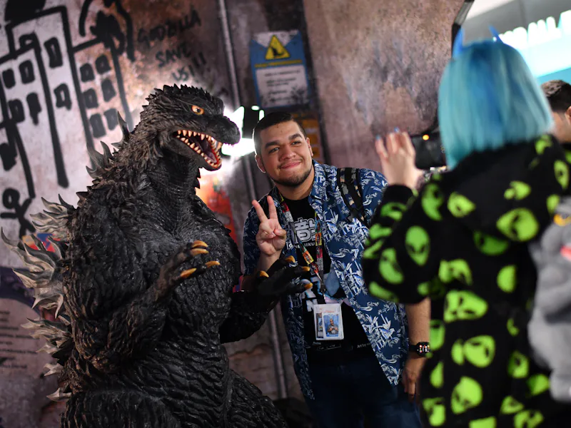 An attendee poses for photos with Godzilla during Comic-Con International in San Diego, California, ...