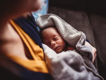 Male newborn (one month) sleeps soundly in his pajamas at home.