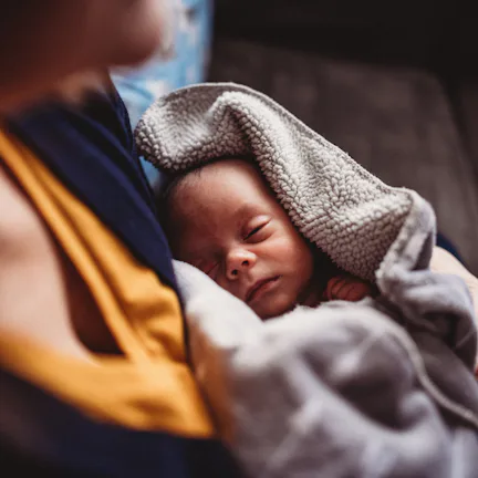 Male newborn (one month) sleeps soundly in his pajamas at home.