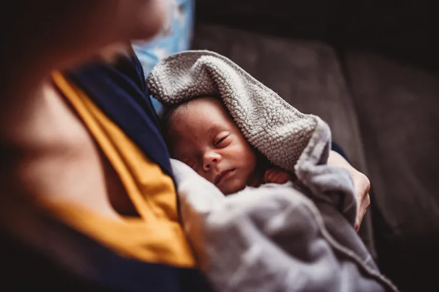 Male newborn (one month) sleeps soundly in his pajamas at home.