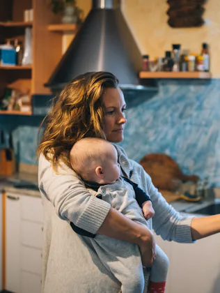 She is getting something from fridge while holding baby