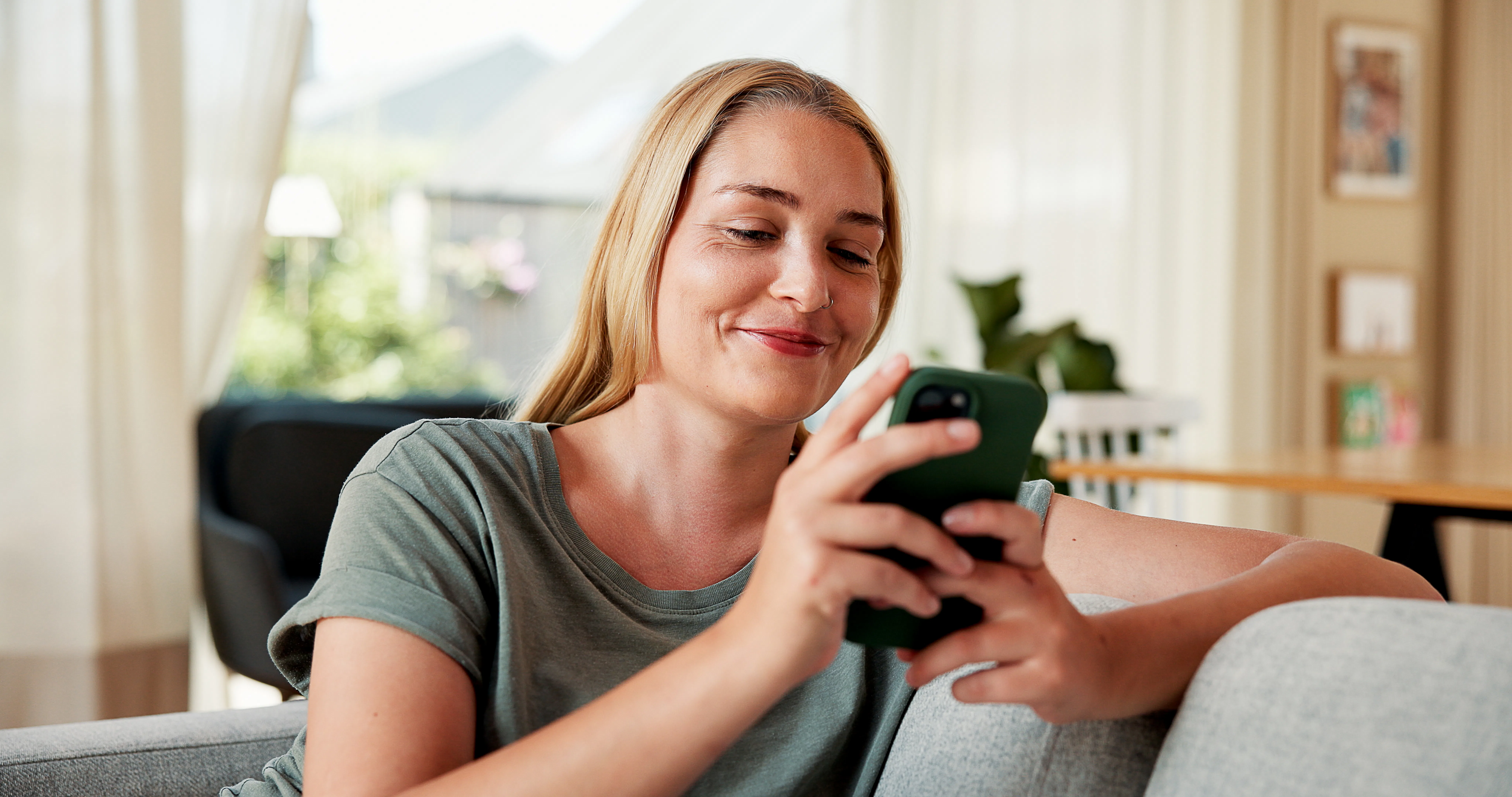 Happy, home and woman on sofa, smartphone and relax with online chatting, internet and texting. Apar...