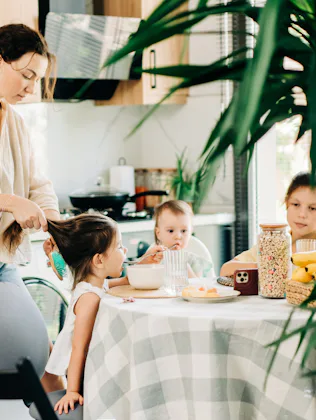Mother helping children with breakfast in the kitchen.