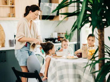 Mother helping children with breakfast in the kitchen.