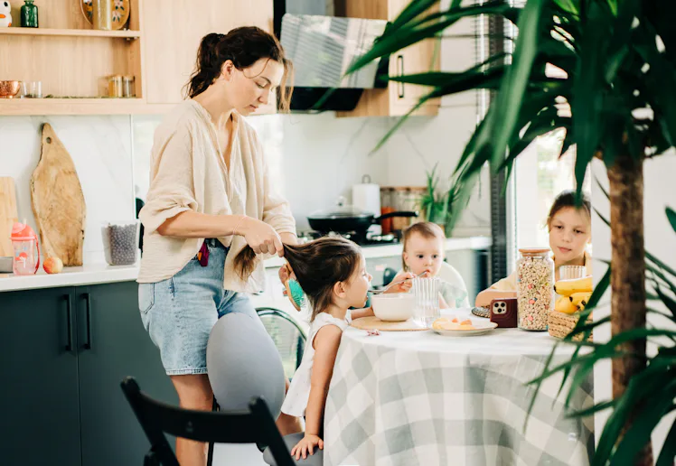 Mother helping children with breakfast in the kitchen.