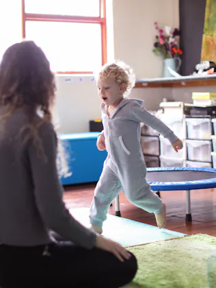 a Toddler and his mother playing in the playroom at home.
