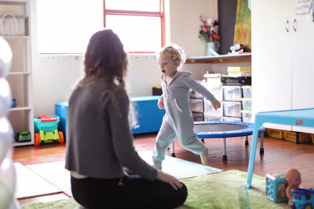 a Toddler and his mother playing in the playroom at home.