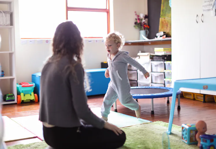 a Toddler and his mother playing in the playroom at home.