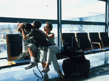 A mom and her two kids wait for a plane in an airport.