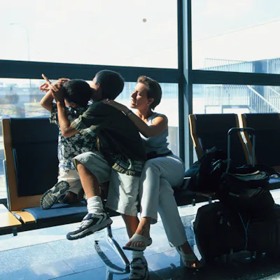 A mom and her two kids wait for a plane in an airport.