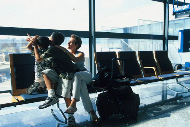 A mom and her two kids wait for a plane in an airport.