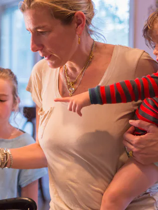 Exhausted mom cooking dinner with her two kids close by in a story about dealing with the monotony o...