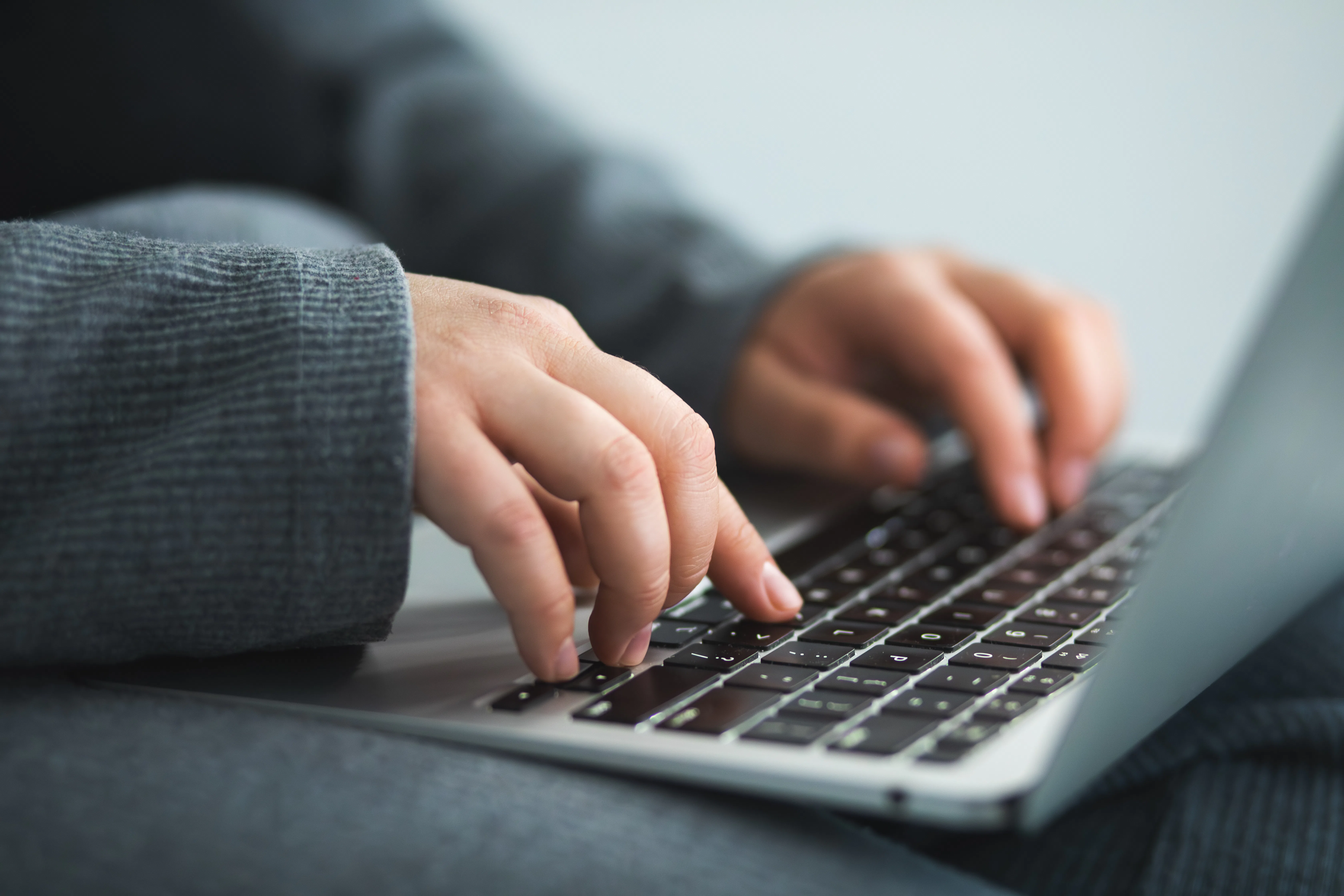 Person's hands typing on a laptop computer keyboard, sending emails, online messaging, learning, cha...