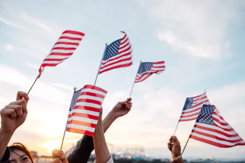 A group of people holding small flags of the USA in their hands