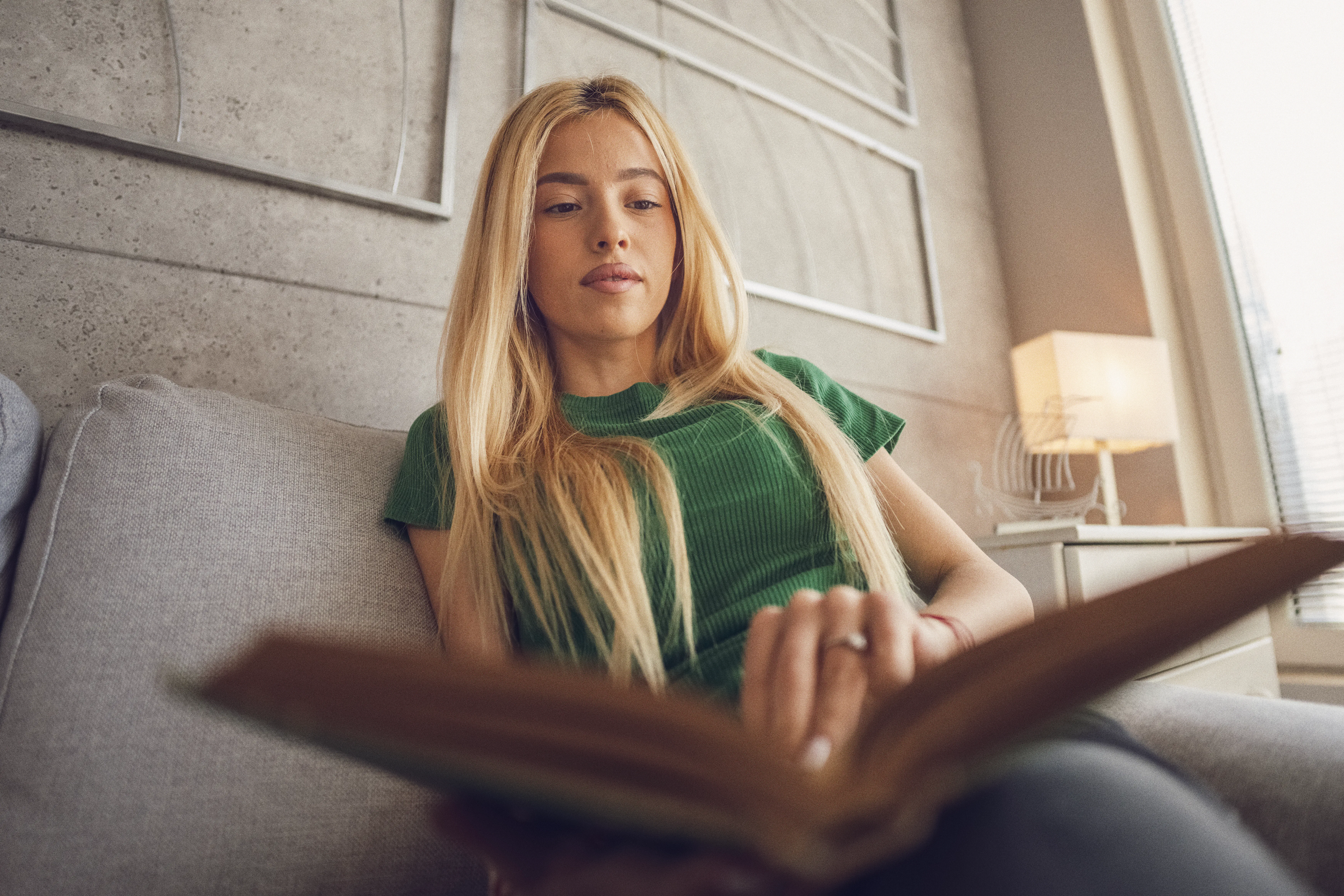 Women wellness. Low angle view of beautiful Gen Z Asian woman reading book in calm cozy home atmosph...
