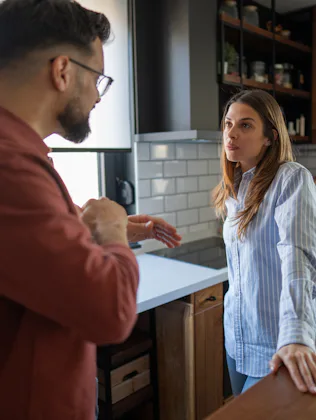 Couple having a difficult conversation in their kitchen, experiencing relationship problems, conflic...