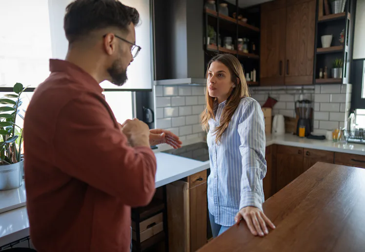 Couple having a difficult conversation in their kitchen, experiencing relationship problems, conflic...