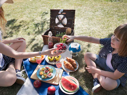 Mother and child share a bowl of raspberries and blueberries surrounded by drinks, croissants and fr...