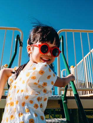 Joyful little Asian girl having fun playing at jungle gym in an outdoor playground on a lovely sunny...