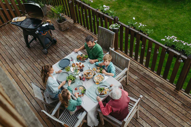 Top view of multigenerational family sitting at big dining table, enjoying grilled food. Family barb...