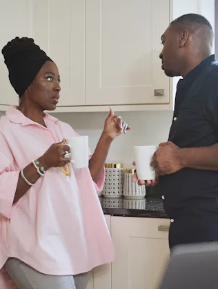 Morning, coffee and a black couple in the kitchen of their home together for conversation or bonding...