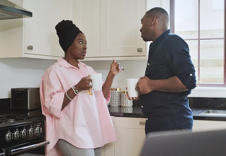 Morning, coffee and a black couple in the kitchen of their home together for conversation or bonding...