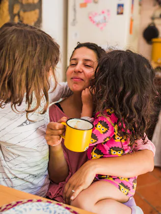 Mother embracing her daughters enjoying a morning moment together at home