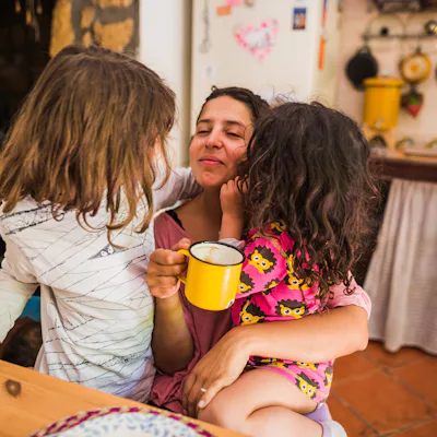 Mother embracing her daughters enjoying a morning moment together at home