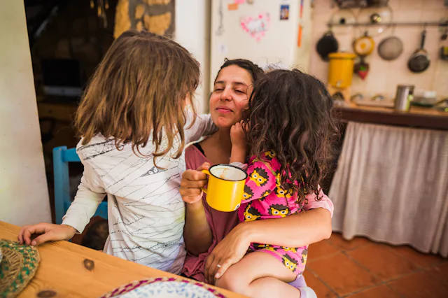Mother embracing her daughters enjoying a morning moment together at home