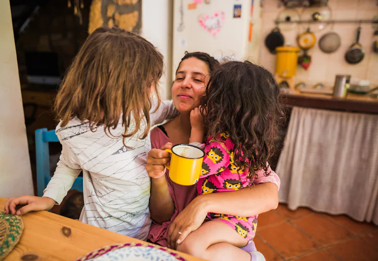 Mother embracing her daughters enjoying a morning moment together at home
