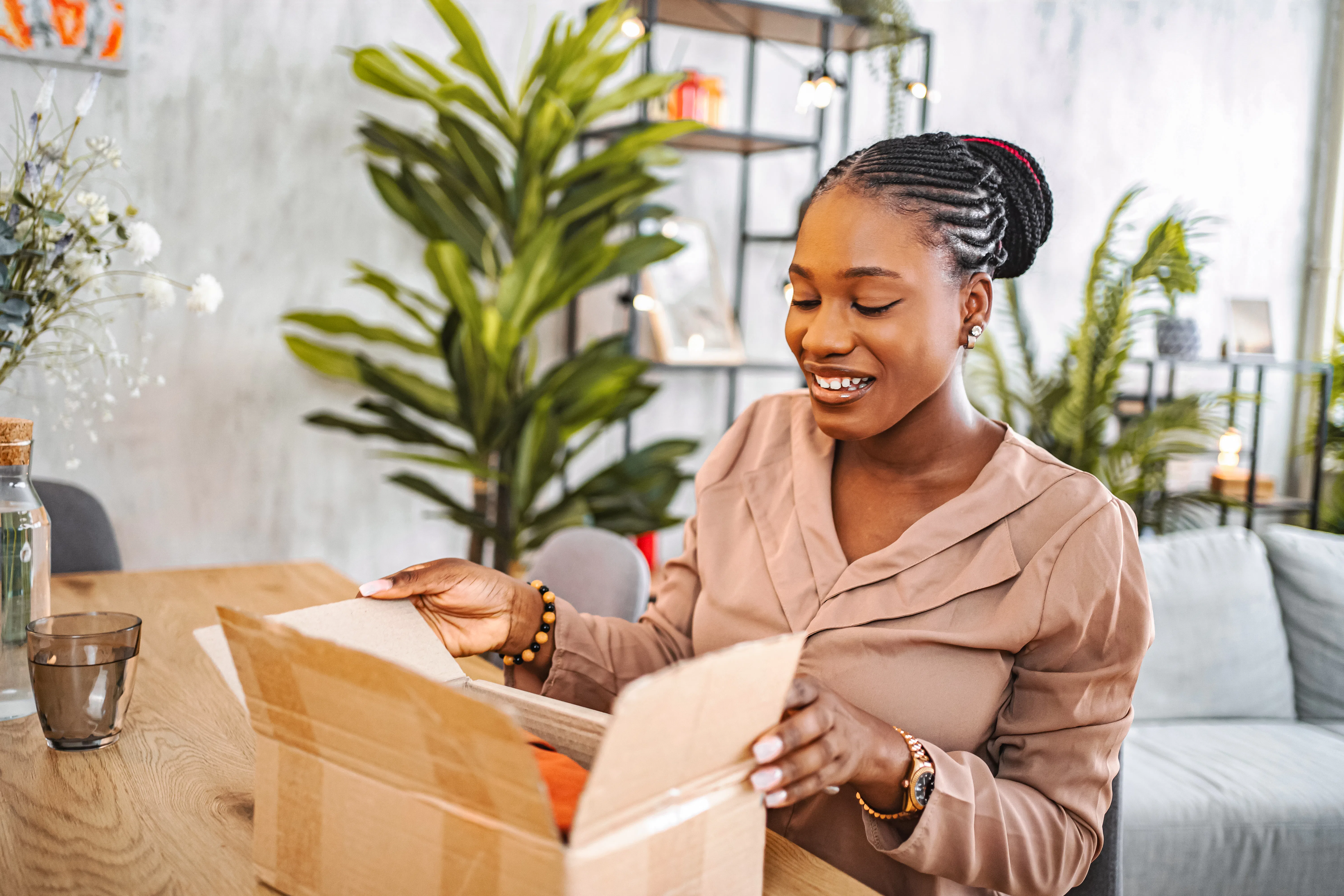 Young adult woman opening a delivered cardboard box with a cheerful expression